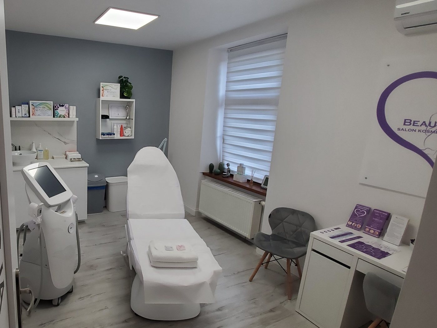 Gabinet depilacji laserowej w salonie Beautiful Skin: laser, fotel zabiegowy, okno i logo salonu na ścianie